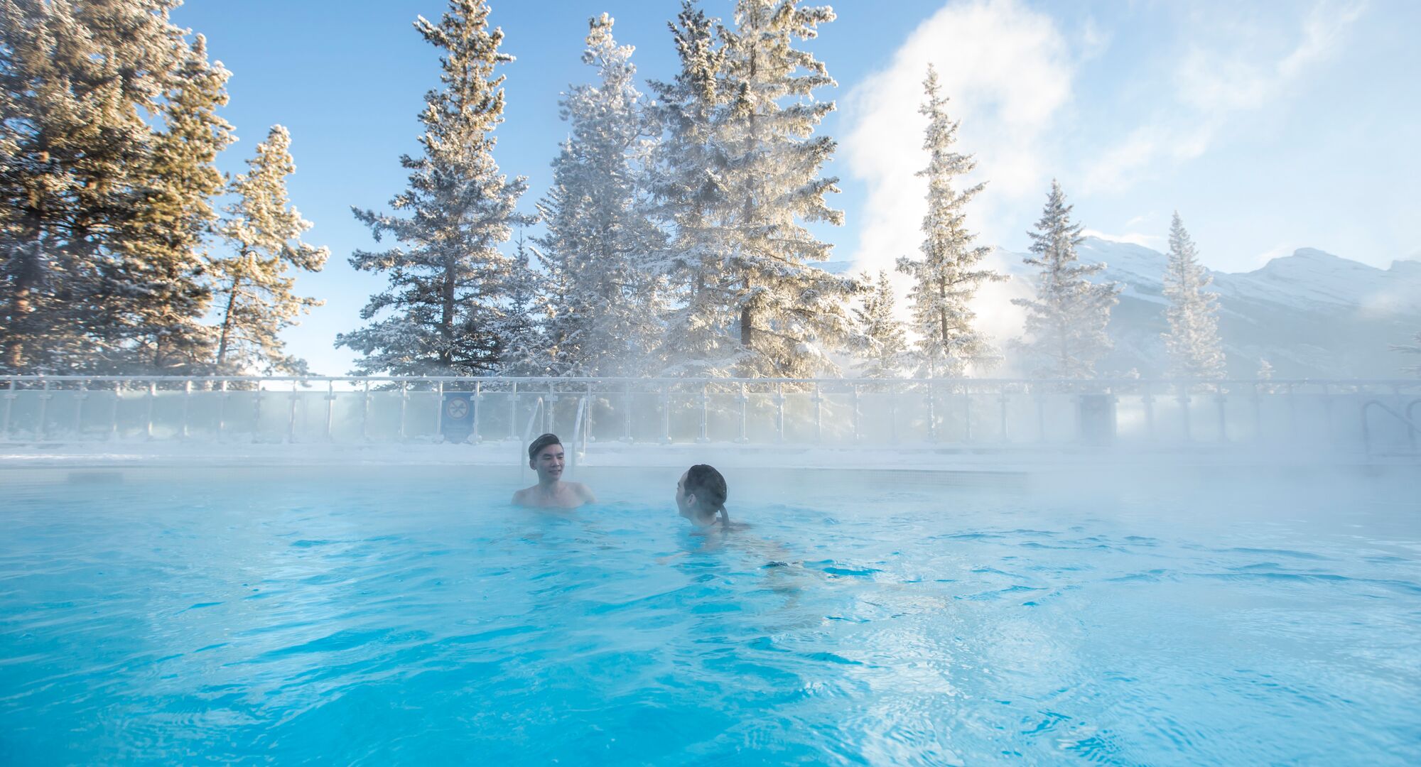 Two people enjoying a soak in the Banff Upper Hot Springs on a cool morning